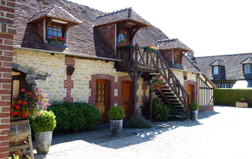 een oud bakstenen huis met bloemen op een binnenplaats bij Le Pave d'Hotes in Beuvron-en-Auge