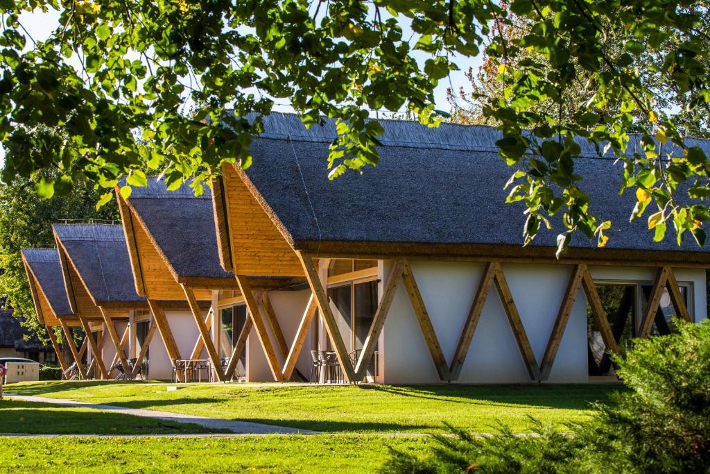 un bâtiment avec un toit en gambrel sur une pelouse dans l'établissement Hotel Ajda Depandance Prekmurska Vas - Terme 3000 - Sava Hotels & Resorts, à Moravske Toplice