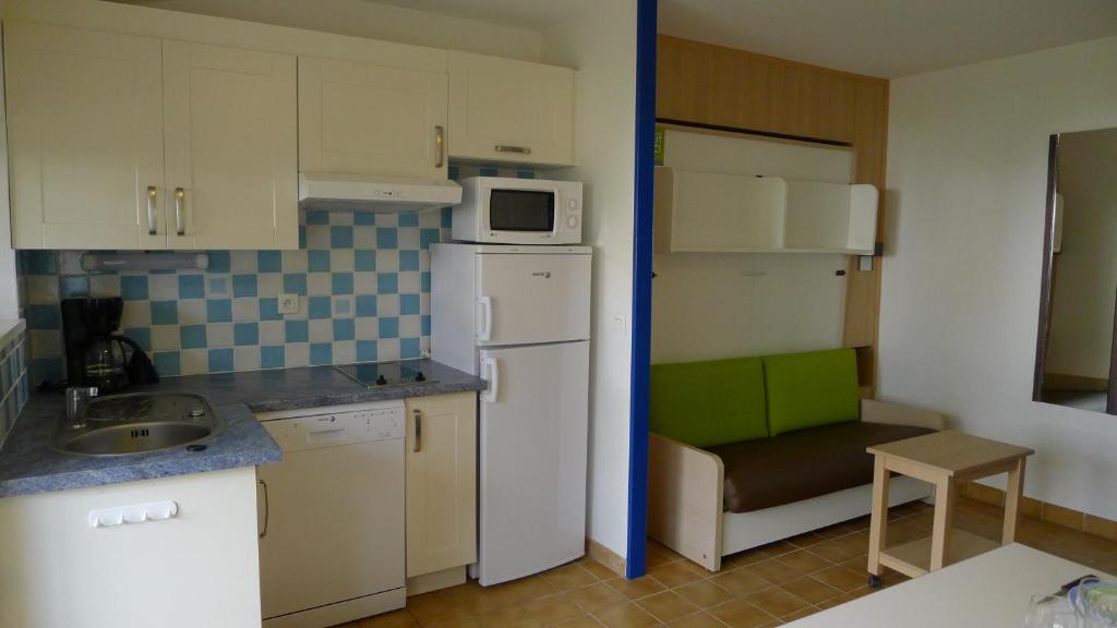 a small kitchen with a white refrigerator and a microwave at Village Océanique in Le Bois-Plage-en-Ré