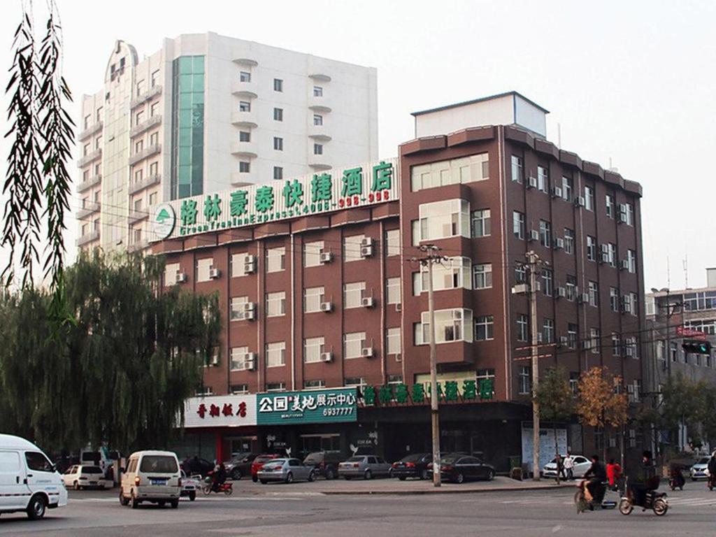 un edificio en una calle de la ciudad con coches y edificios en GreenTree Inn Taiyuan South Inner Ring Qiaoxi Branch en Taiyuán