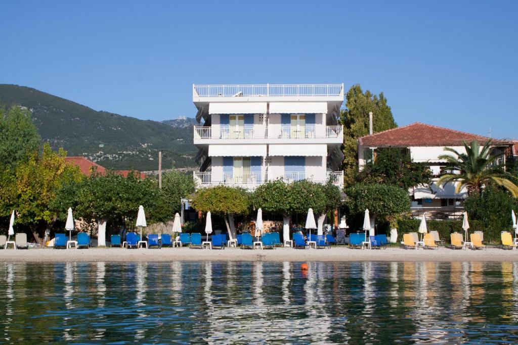 un hotel en la playa con sillas y sombrillas en Hotel Nydri Beach en Nydri