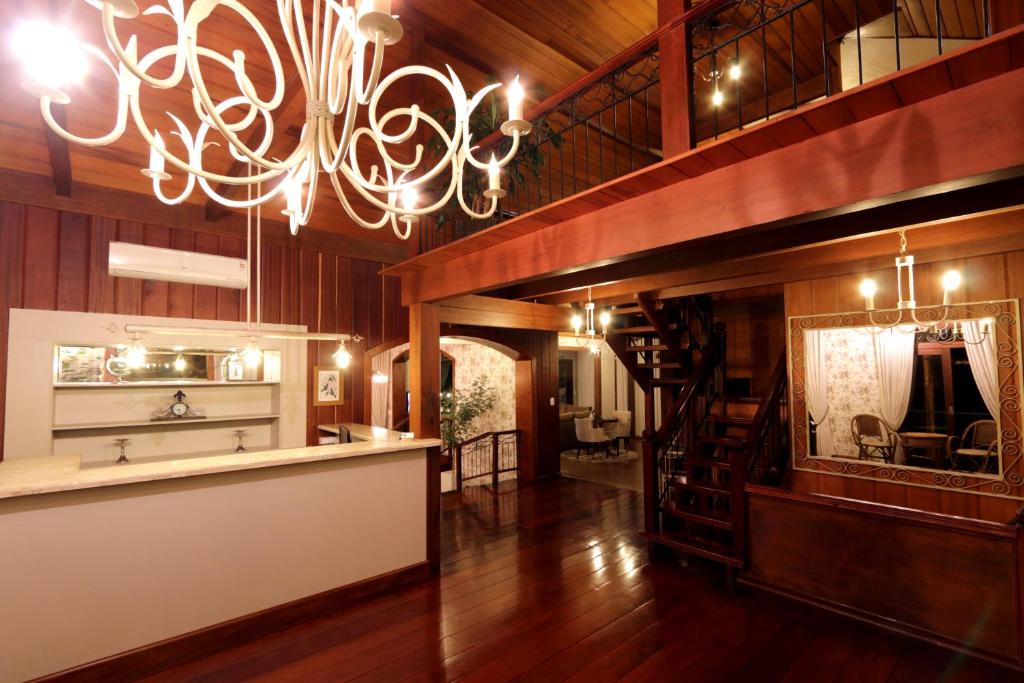 um quarto amplo com pisos em madeira e um lustre em Pousada do Verde Gramado em Gramado
