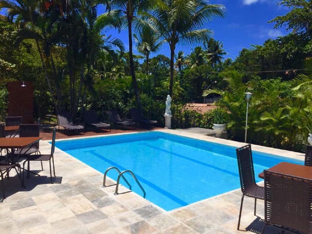 uma piscina com cadeiras e uma mesa em Pousada Tropical em Arraial d'Ajuda