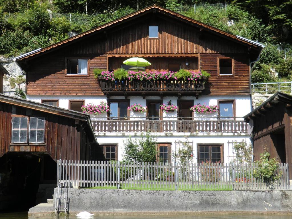 ein Haus mit einem Balkon mit Blumen und einem Sonnenschirm in der Unterkunft Fewo Wakolbinger-Wieder in Hallstatt