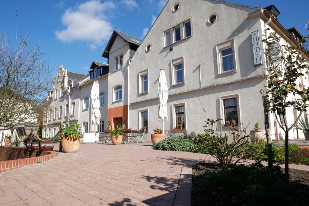 un gran edificio blanco con macetas en un patio en Hotel Garni Brauhof Niederwiesa en Niederwiesa