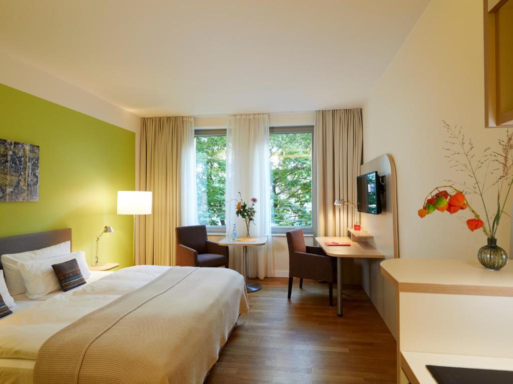 ein Hotelzimmer mit einem großen Bett und einem Schreibtisch in der Unterkunft Flottwell Berlin Hotel & Residenz am Park in Berlin