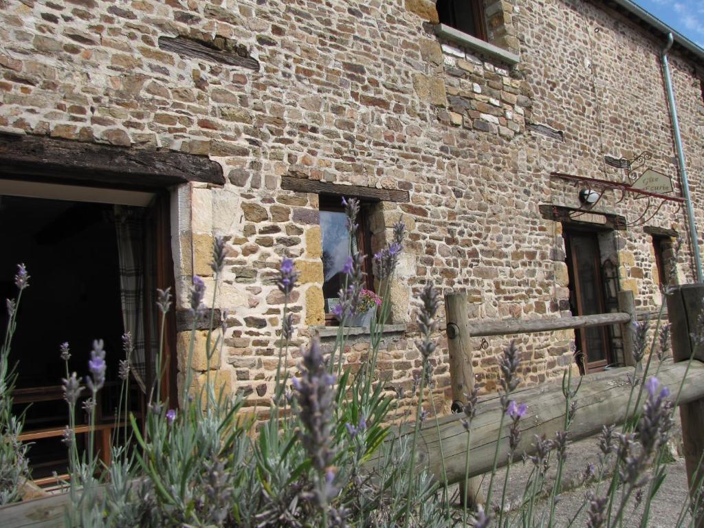 un bâtiment en briques avec des fleurs devant lui dans l'établissement L'ECURIE GITE, à La Pommeraye