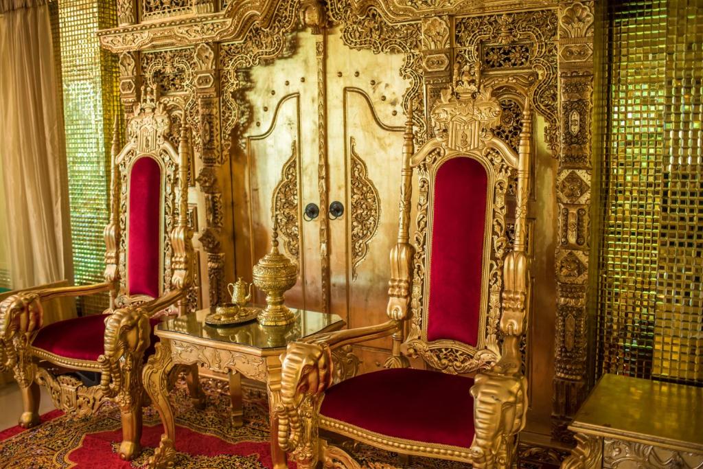 un trône d'or dans une pièce avec des chaises rouges dans l'établissement Nakaraj Princess Chiang Rai - Walking Street, à Chiang Rai