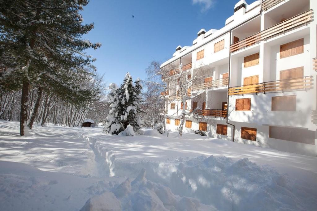 un patio cubierto de nieve de un edificio con árboles en Quadrifoglio, en Campo di Giove