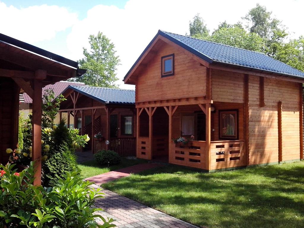 uma cabana de madeira com um alpendre e uma casa em ROSSA - Domki Letniskowe em Międzywodzie