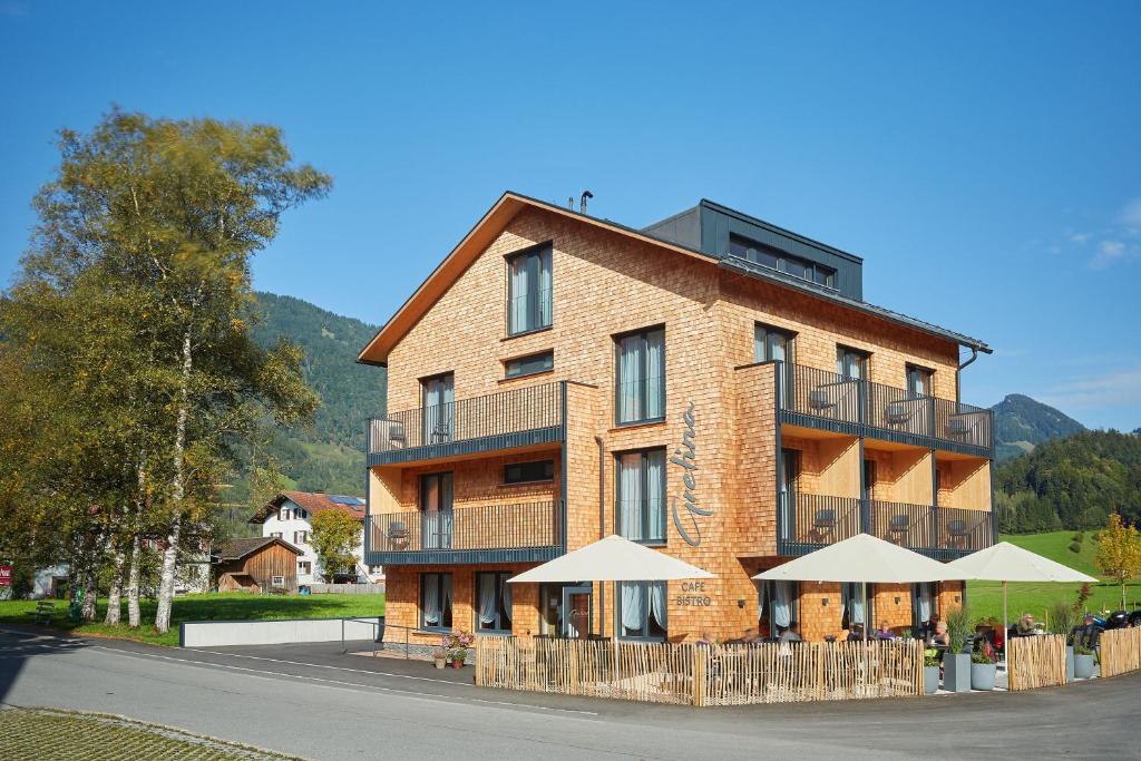 un grande edificio in mattoni con ombrelloni di fronte di Hotel Gretina a Bezau