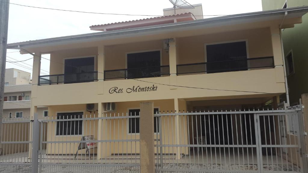 ein großes gelbes Haus mit einem Zaun davor in der Unterkunft Residencial Montoski in Bombinhas