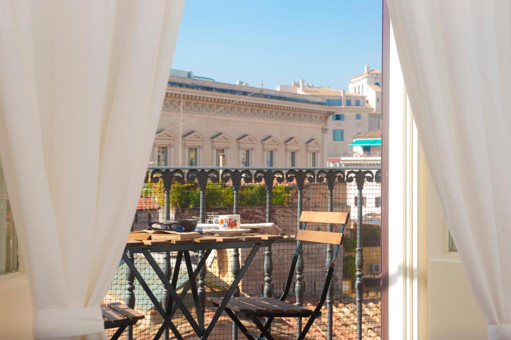 einen Tisch und Stühle auf einem Balkon mit Blick auf ein Gebäude in der Unterkunft Monti Deluxe - Terrace Spectacular View in Rom