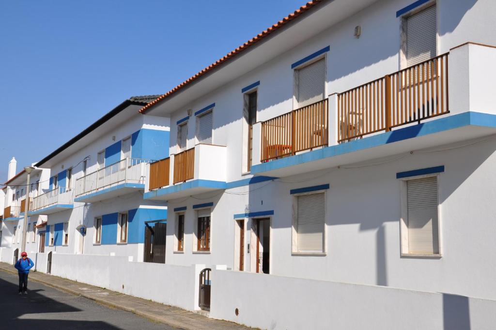 a person walking down a street next to a building at Apartamentos Campos 1 in Porto Covo