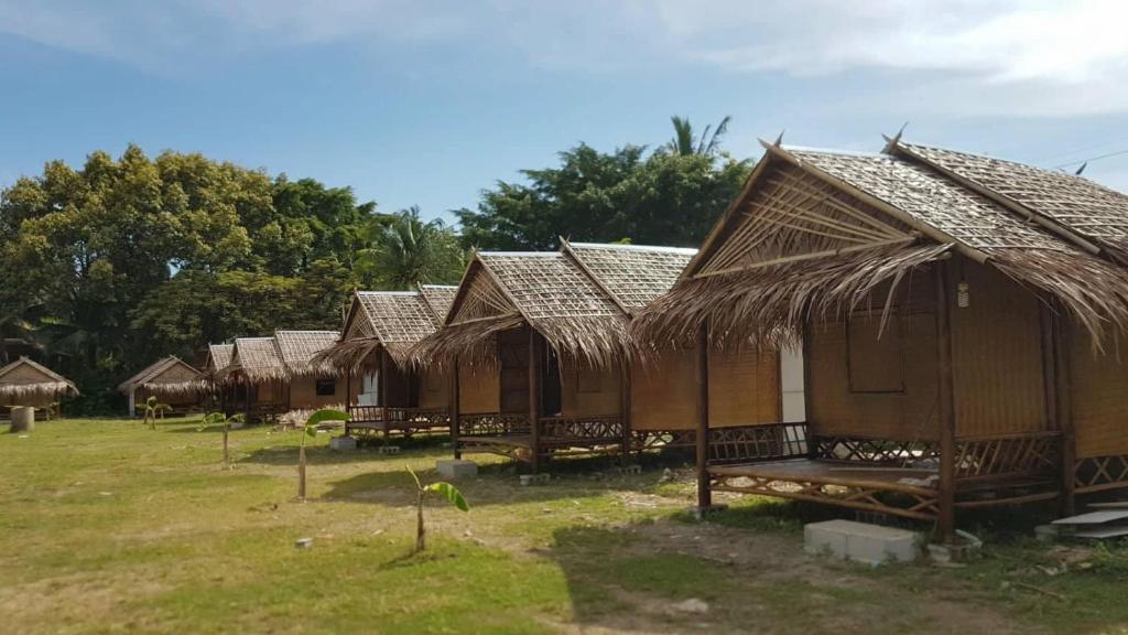 una fila de cabañas con techos de paja en un campo en Lanta Local Hut, en Ko Lanta