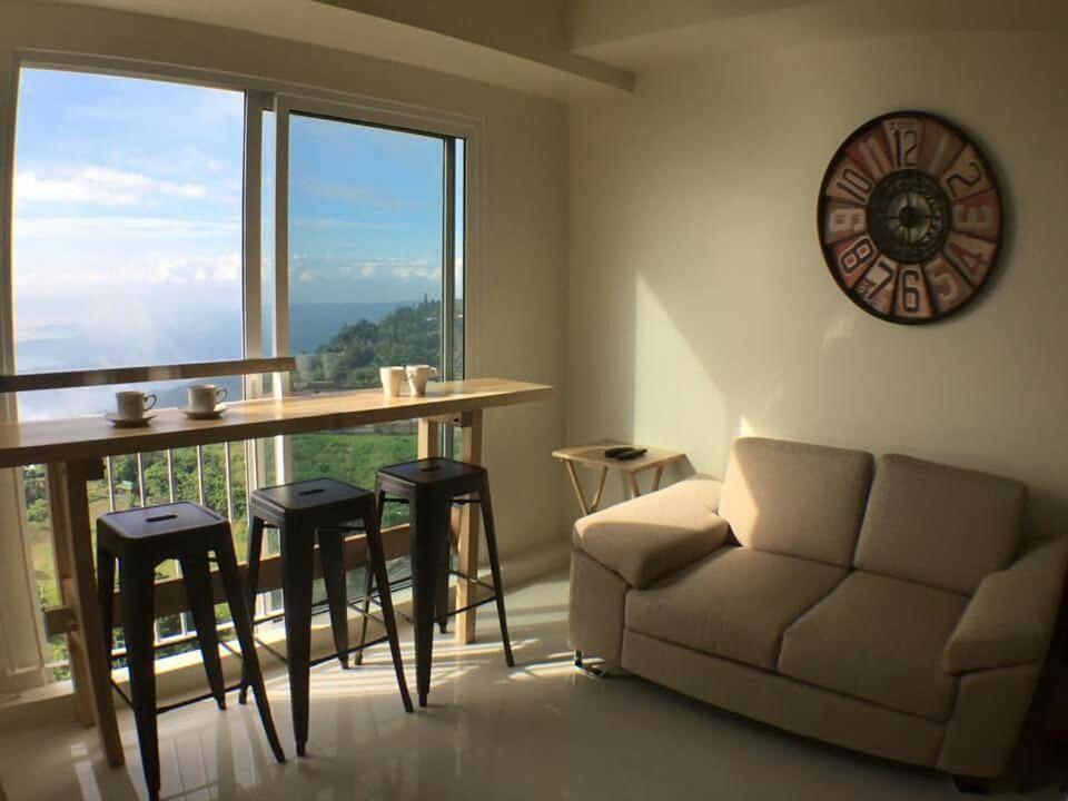 a living room with a couch and a table and a large window at AMS Staycation at Wind Residences in Tagaytay