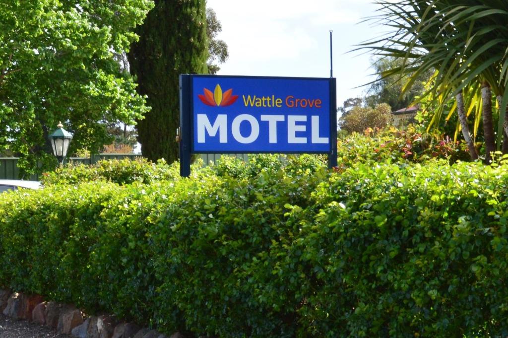 a sign for a motel in front of a hedge at Wattle Grove Motel Maryborough in Maryborough