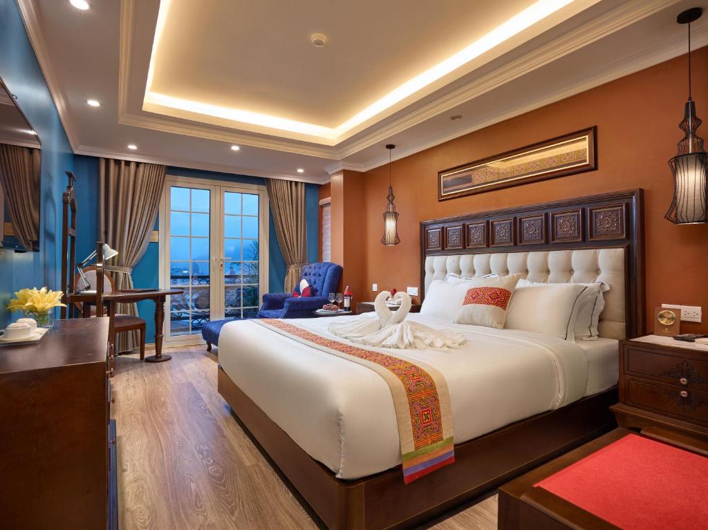 een grote slaapkamer met een groot bed en een bureau bij Eden Boutique Hotel & Spa in Sa Pa