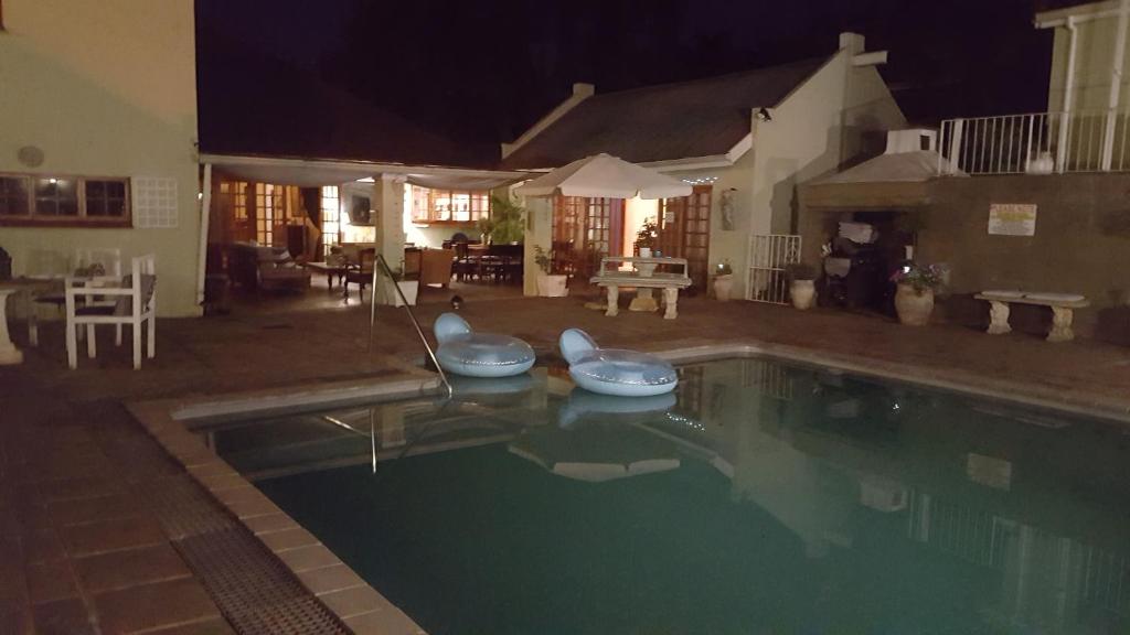 a swimming pool at night with chairs in it at Apartment 7 On Oakleigh in Pietermaritzburg