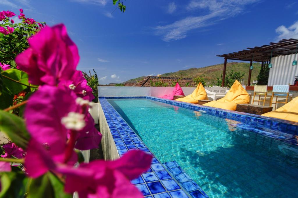 a swimming pool with chairs and purple flowers at Rawa Lombok in Kuta Lombok
