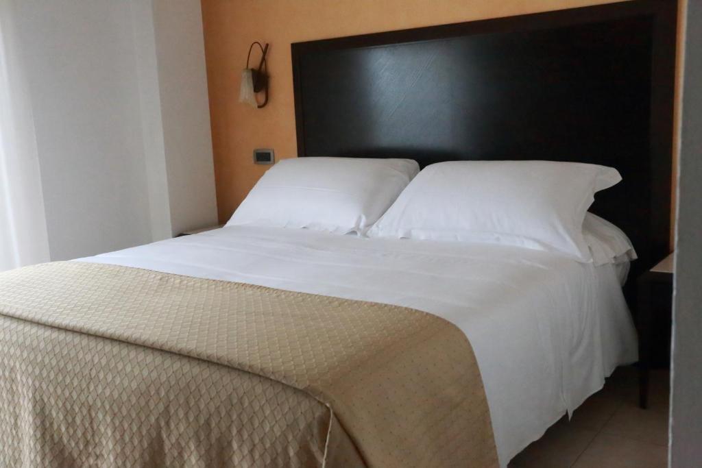 a bedroom with a large white bed with a black headboard at Hotel Du Soleil in Rimini