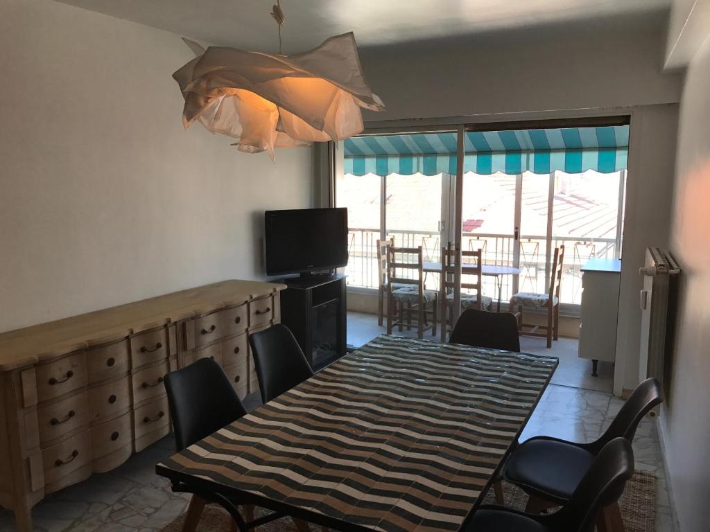 a dining room with a table and chairs and a television at Les Jacinthes in Saint-Raphaël