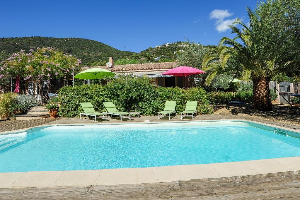 a swimming pool with lawn chairs and umbrellas at Les Ilets de L'Eau Blanche in Cavalaire-sur-Mer