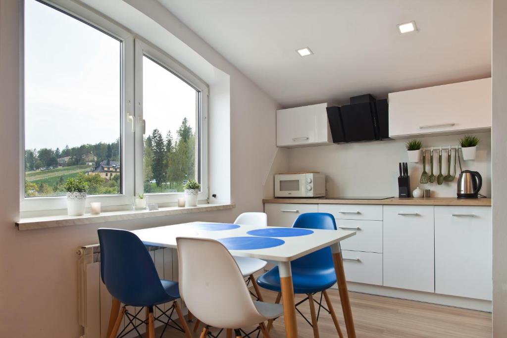a kitchen with a table and some blue chairs at Apartament City Center Best View in Krynica Zdrój