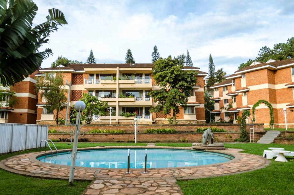 a courtyard with a swimming pool in front of a building at Golf Course Apartments in Kampala