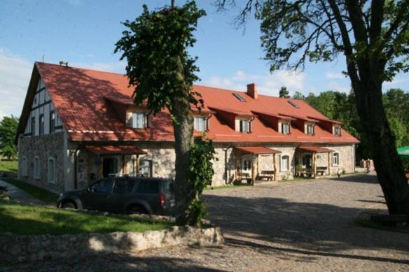 duży dom z samochodem zaparkowanym przed nim w obiekcie Ūdensdzirnavas w mieście Strazde