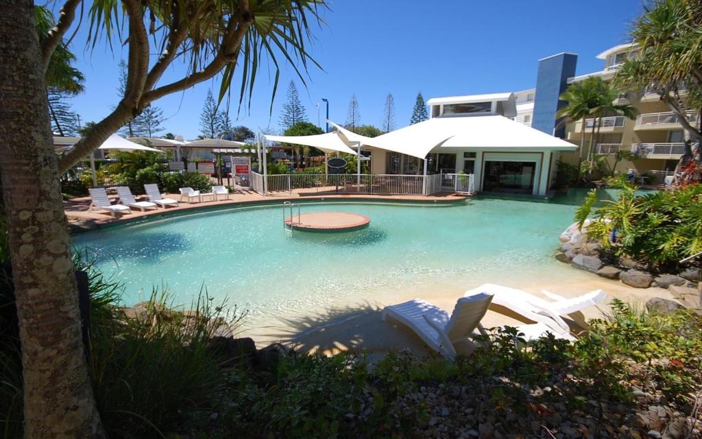 Alexandra Headland的住宿－亞歷克斯海灘度假村305室，度假村内带椅子和遮阳伞的游泳池