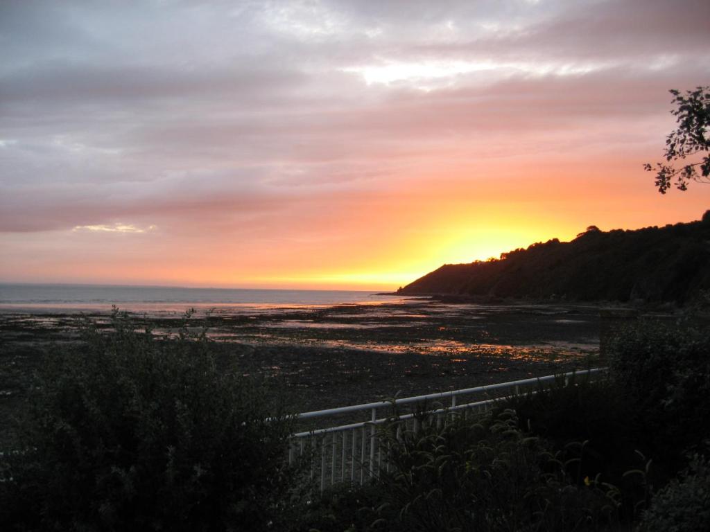 a sunset over a beach with the ocean at A l'abri des vents in Saint-Jean-le-Thomas