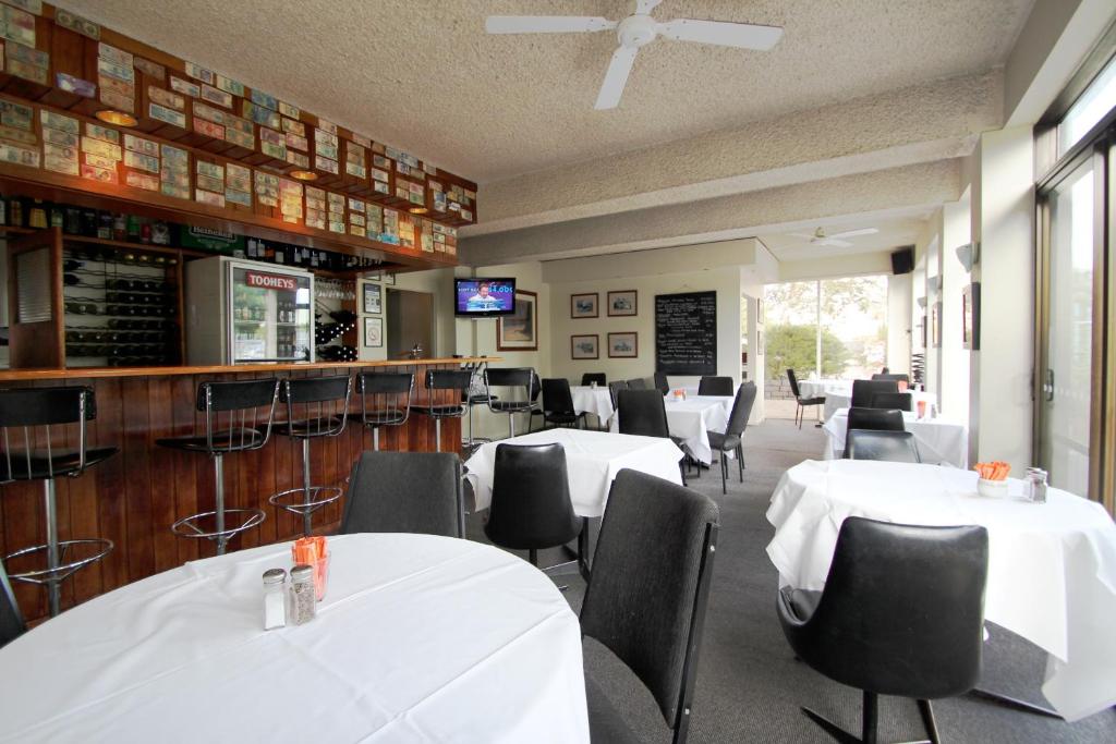 a dining room with white tables and chairs at Beaumaris Bay Motel in Beaumaris