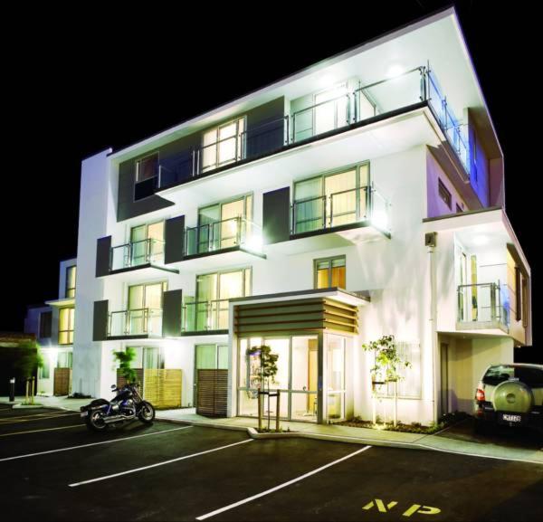een wit gebouw met een motorfiets ervoor geparkeerd bij Focus Motel in Christchurch