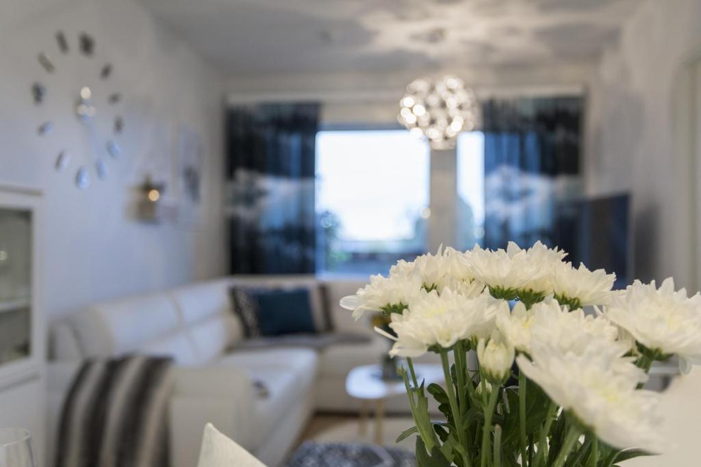 un vase de fleurs blanches sur une table dans le salon dans l'établissement Tuomas' Luxurious Suites, Nilo, à Rovaniemi
