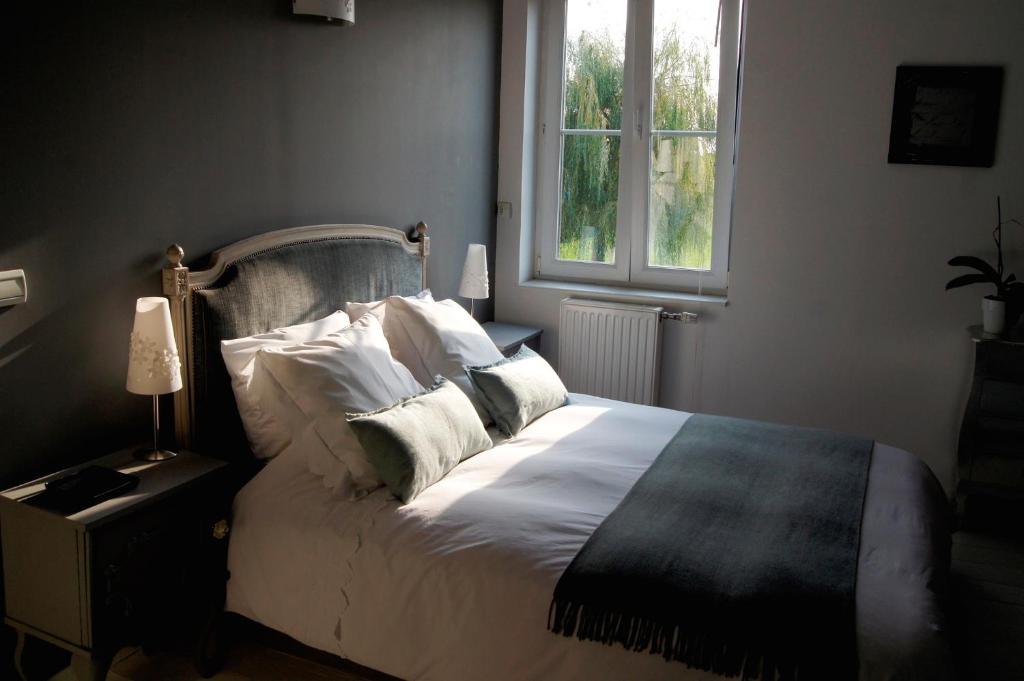 1 dormitorio con cama con almohadas y ventana en Chambres d'Hôtes La Parenthèse en Wambrechies
