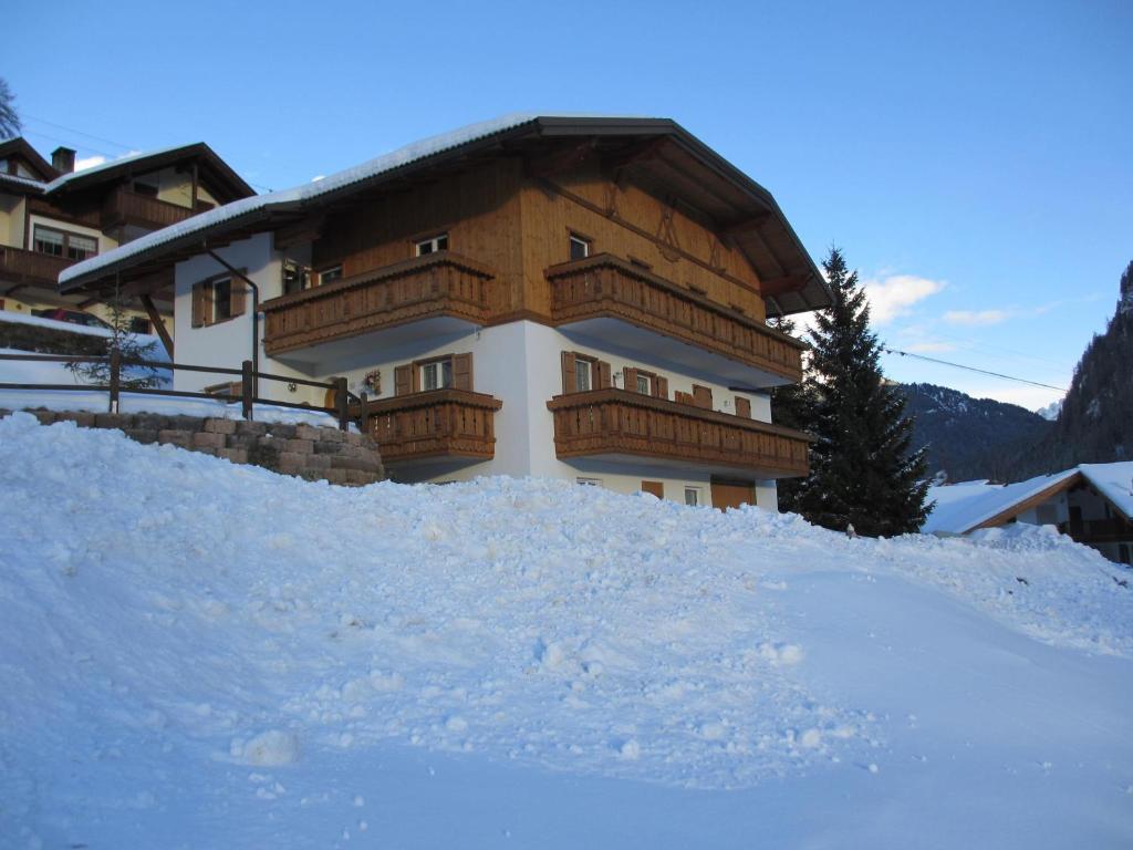 un grand bâtiment avec un balcon dans la neige dans l'établissement Cèsa Chri e Sofì, à Campitello di Fassa