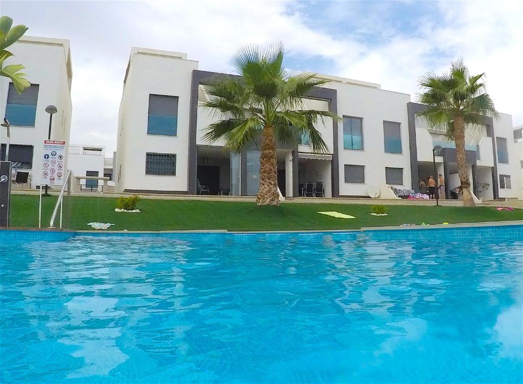 einem Pool vor einem Gebäude mit Palmen in der Unterkunft Penthouse La Zenia in Playa Flamenca