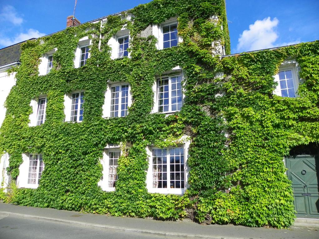 un bâtiment recouvert de lierre vert dans une rue dans l'établissement Chambres d'hôtes du Perray, à Candé