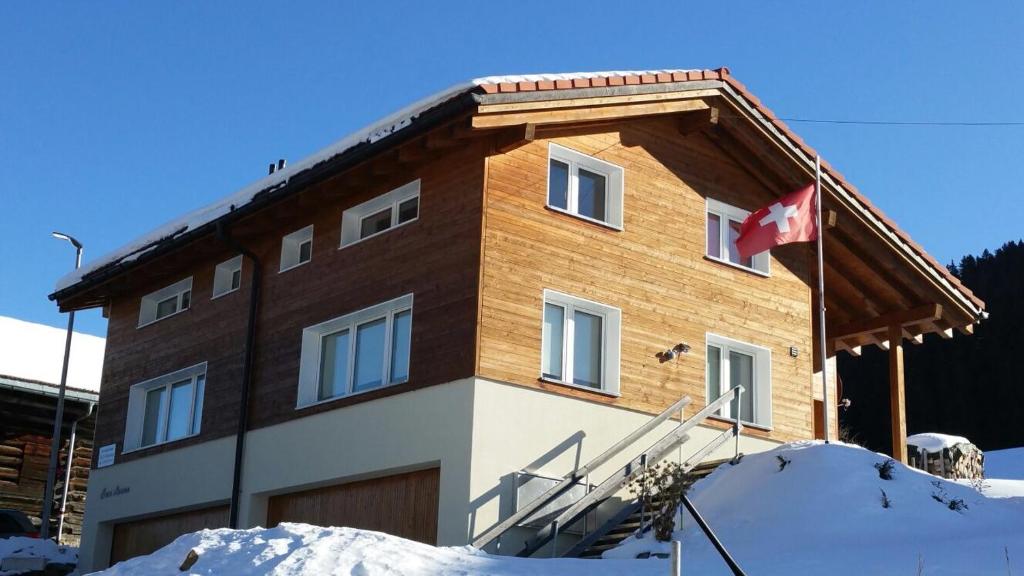 ein Haus mit einer kanadischen Flagge davor in der Unterkunft Casa Aurora in Sedrun