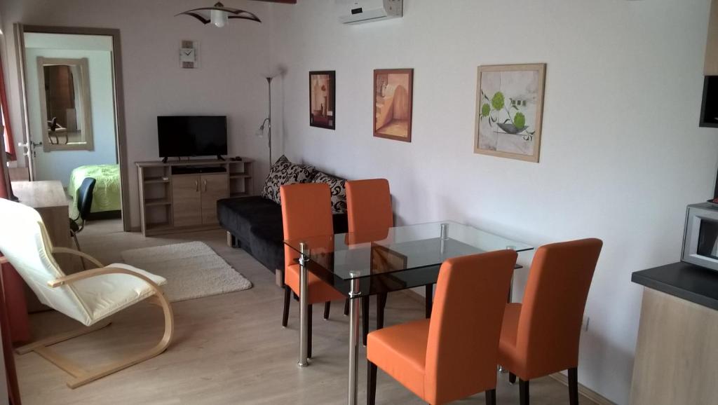 sala de estar con mesa de cristal y sillas de color naranja en Gereben Apartman Pécs, en Pécs