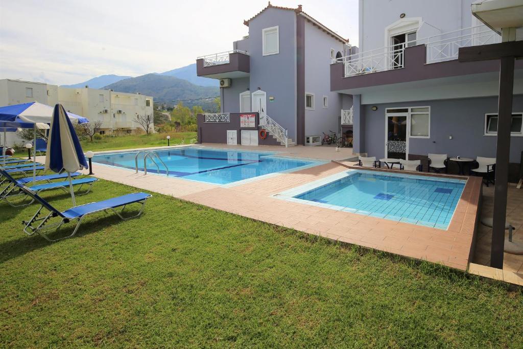 una piscina con 2 tumbonas junto a una casa en Athena Hotel en Georgioupolis