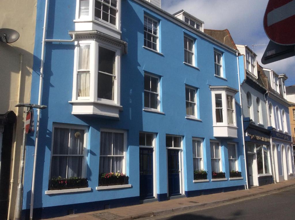 a blue building with white windows on a street at Olde Lantern Holiday Lets in Ilfracombe