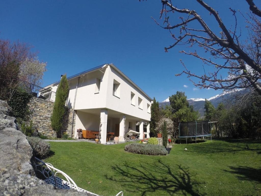 a white house with a yard with green grass at BnB Chantevent in Sierre