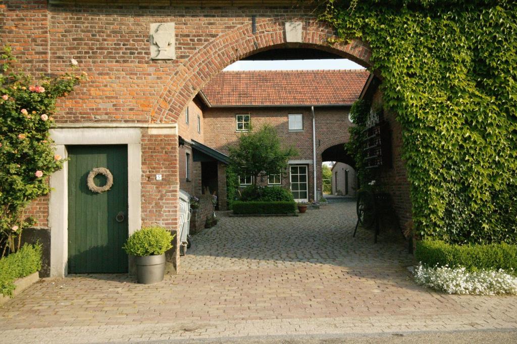 un arco en un edificio de ladrillo con una puerta verde en Recreatie Landgoed Terlingerhoeve, en Noorbeek