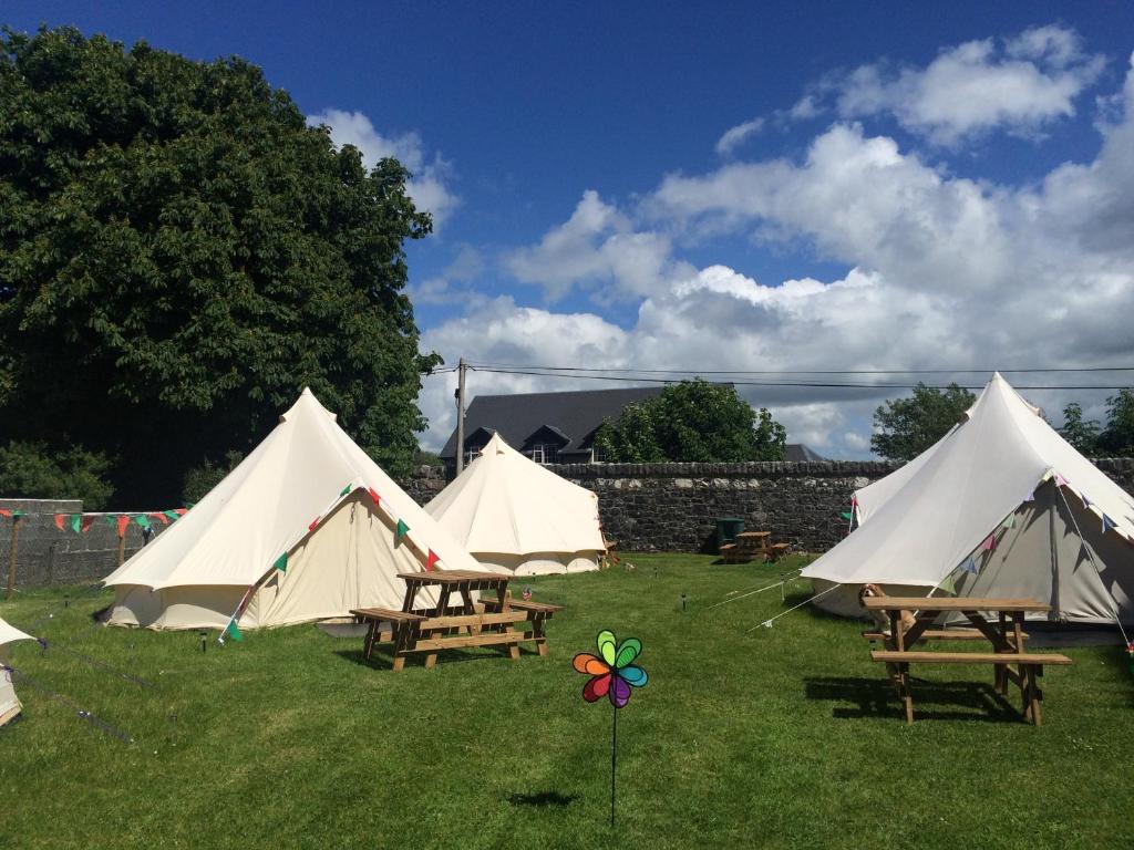 eine Gruppe von Zelten auf einem Feld mit Tischen und Bänken in der Unterkunft Cong Glamping in Cong