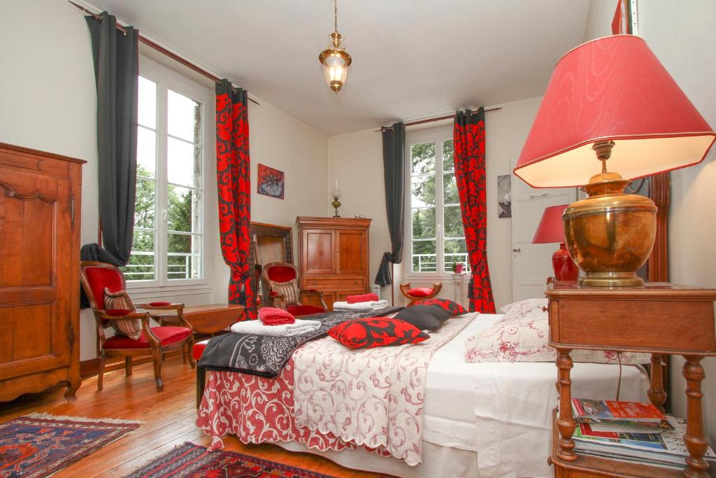 een slaapkamer met een bed en een rode lamp bij Manoir des Turets in Yvré-lʼÉvêque