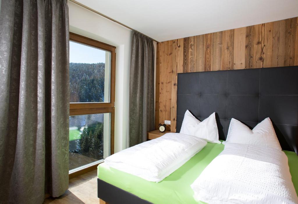 a bedroom with a large bed with a large window at Familyparadies GAMPLALM in Lana