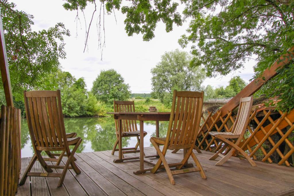 three chairs and a table on a deck with a lake at Manoir des Turets in Yvré-lʼÉvêque