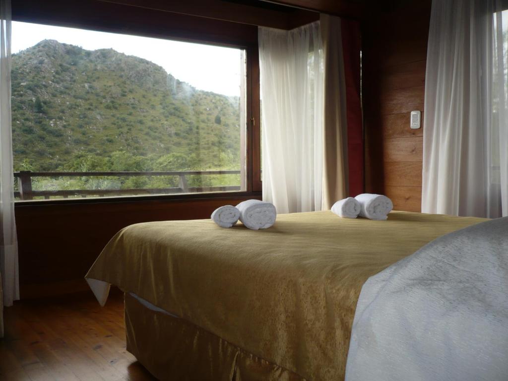 a bedroom with a bed with a large window at Arroyo Escondido in La Cumbrecita